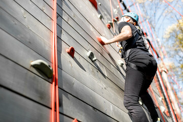 Fototapeta na wymiar Well-equipped man climbing the wall outdoors in the park for sports entertainment