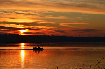 Two people on the boat among the river, golden sunset photo, rest