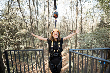 Young woman feeling free and happy before a bungee jump from the tower in the rope park