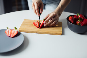Close-up of the hands of a girl who cuts strawberry. Healthy food