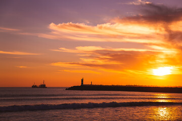 Fototapeta na wymiar sunset on the beach in the Atlantic ocean Viana do Castelo Praia do Cabedelo Cabedelo beach colorful clouds with a lighthouse boat
