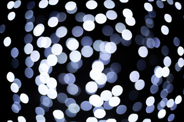 grey and white blurred spots from the garland on the black background. Blurred abstract white and blue spot lights isolated on dark background. new year and christmas bright background 