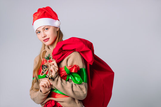 Santa Claus girl in New Year's outfit with and a big red bag of gifts on a white background. Wish and holidays concept.