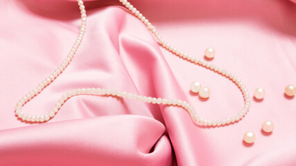 pearl beads on pink luxury satin fabric. Background. elegant wallpaper