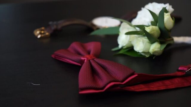 men's attributes, red bow tie, men's wrist watch and flowers in buttonhole boutonniere