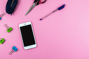 Stationery set, pens and office supplies, smartphone on peach background, flat lay, copy space