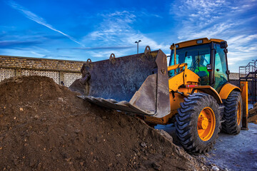 Stopped yellow excavator with shovel at construction site