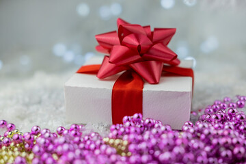 surprise gift with red bow on snow on bokeh background