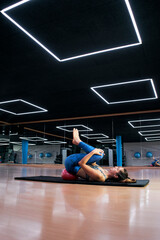 A Caucasian woman exercising pilates fitness ball exercises in a modern gym.