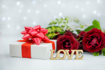 gift box with a red bow on a background of flowers roses