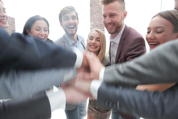 close up. a group of successful young people putting their hands together
