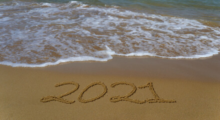 Happy new year 2021 written in the sand.Happy new year 2021 written in the sand by the sea.