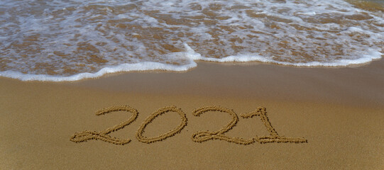 Happy new year 2021 written in the sand.Happy new year 2021 written in the sand by the sea.