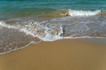 Fototapeta na wymiar Foamy Wave On The Sandy Beach.Beautiful wave on the beach.