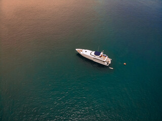 Fototapeta na wymiar Drone shot of the beautiful white yacht in the warm blue sea; millionaire concept.