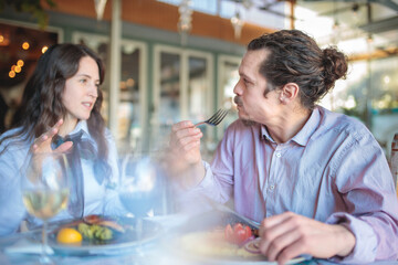 Serious young hispanic man talking with his wife or girlfriend while having lunch in a rustic restaurant