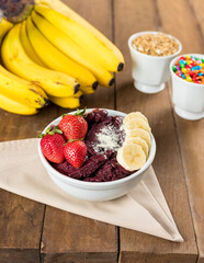 Brazilian Açai on a white pot with straw berry, banana and powdered milk on a wooden background and fruits at summer
