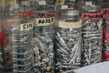 Obraz premium Several small buckets with bolts and plugs are standing in a row in a store, close up