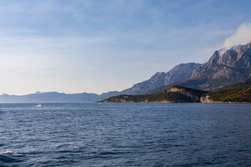 Fototapeta na wymiar Blick vom Meer auf die Küste in Kroatien. Berge mit Rauchwolken am Himmel