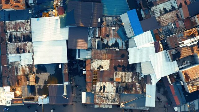 Aerial top-down view of a bazaar in a slum with people between the rows.
