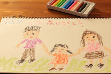 クレヨンでスケッチブックに描かれた家族の絵