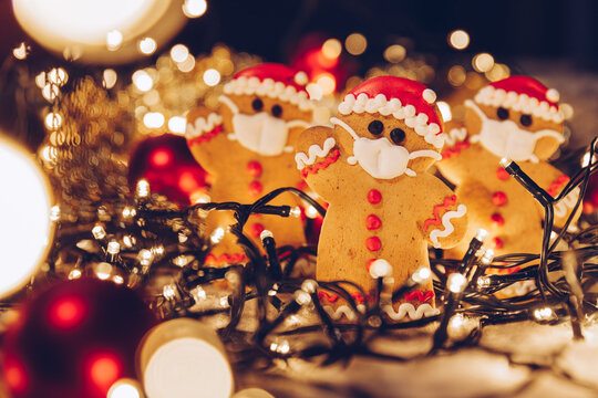 Festive Christmas background with gingerbread men wearing a medical protective mask on their faces. The concept of celebrating the New Year 2021 at home during a coronavirus pandemic. Copy space