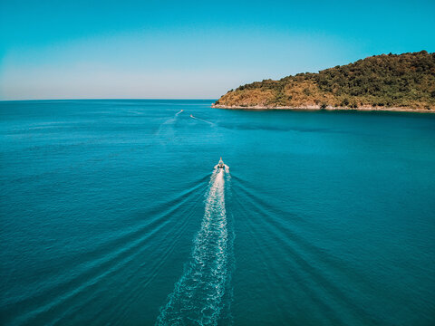 Aerial view, boat is going at full speed in clear blue water right in the middle of the sea