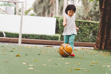 Asian 3 year old kid play football in park. Background for  funny life and family play time.