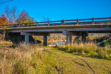 Fototapeta na wymiar A river stream under a bridge and tire tracks in the south