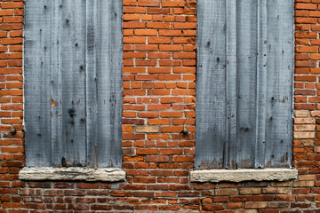 Weathered wooden window coverings and brick wall
