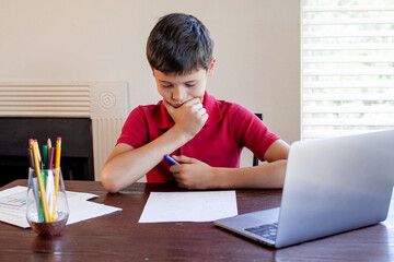 Naklejka premium Distance learning online education. Schoolboy studies at home and does school homework. Concept of home education and distance learning.