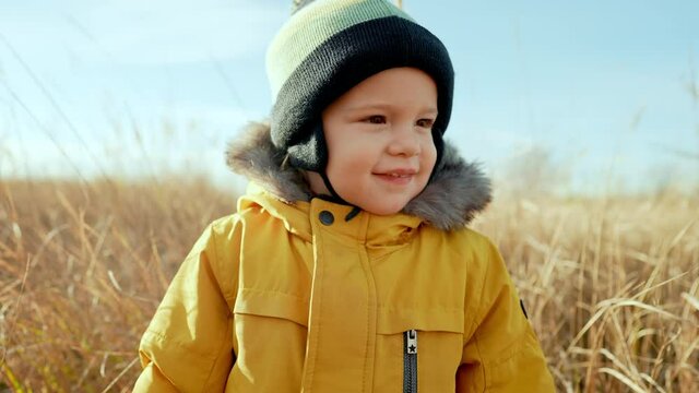 Cute portrait of little toddler baby boy in autumn landscape - park or orange field. Lovely son, family, fall nature concept.