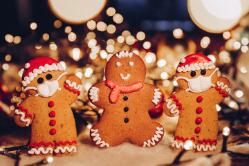 Happy New Year's set of gingerbread man in face mask from ginger biscuits glazed sugar icing decoration on xmas background, colorful seasonal pandemic winter holiday banner