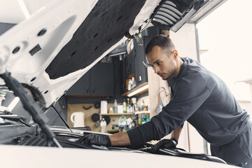 Car detailing series. Cleaning car engine. Man in black uniform.