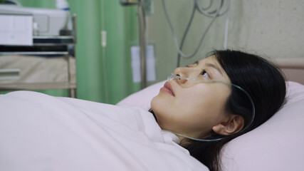 closeup asian chinese woman patient infected with conoravirus and receiving treatment in isolation is lying awake on bed in sorrow