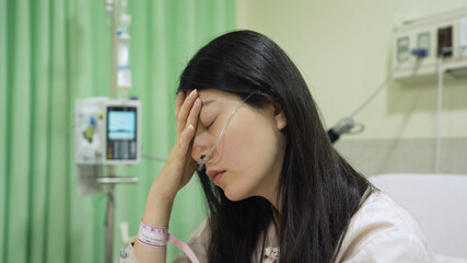 closeup view spiritless patient with nasal tube is touching her forehead in desperation and not...