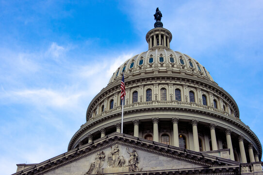 Low Angle View Of American Flag On United States Capitol Building Washington DC With Marble Dome And Blue Sky In Background