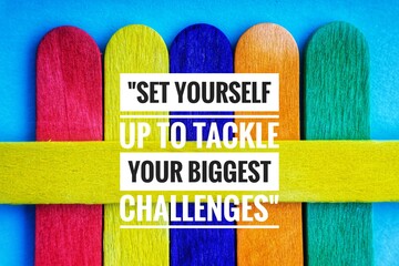 SET YOURSELF UP TO TACKLE YOUR BIGGEST CHALLENGES text and colorful wooden stick on blue background