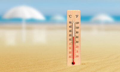 Sea coast at hot summer day. Wooden thermometer in the sand. Ambient temperature plus 19 degrees...