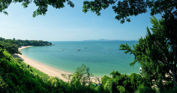 Panorama image of Tropical beautiful seascape view of green trees with blue sea in background at Chonburi, Thailand.