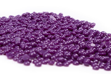 purple wax granules for depilation on a white background close-up
