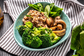 Fresh green vegan salad of fresh spinach, mushrooms, broccoli and quinoa in a bowl, healthy vegan lunch bowl, Food recipe background. Close up