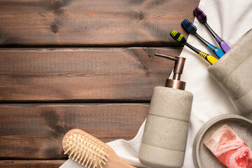 Bath accessories, soap dispenser, comb, towel and toothbrush on the wooden table background with copy space. Hygiene.