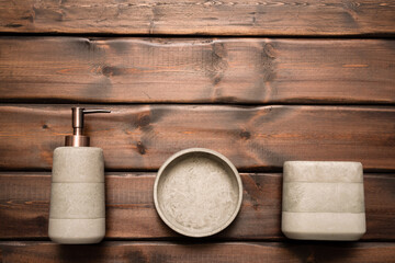 Soap dispenser bottle, toothbrush holder container on the brown wooden table background.