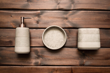 Soap dispenser bottle, toothbrush holder container on the brown wooden table background.