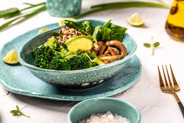 Quinoa salad in bowl with spinach, broccoli, mushrooms and microgreens on a light background. Quinoa superfood concept. Clean healthy detox eating. Vegan vegetarian food