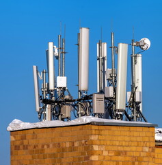 Telephone repeater on the roof of a house against the blue sky in winter