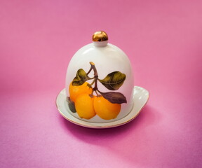 White purchased earthenware patterned saucer with lid for lemon close up on pink background