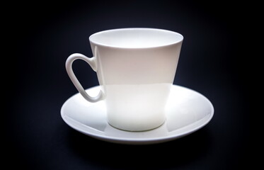 White purchased porcelain coffee Cup with saucer closeup on black background