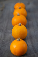 Small orange pumpkins lie in a row on a wooden Board. Background healthy vegetarian food in a geometric form.